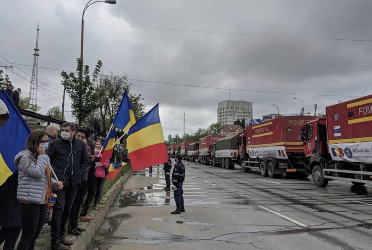 În zonă se adună mai multe persoane, înarmate cu drapeluri românești, pentru a saluta coloana cu peste 20 de camioane, pline cu ajutor umanitar, venite din România