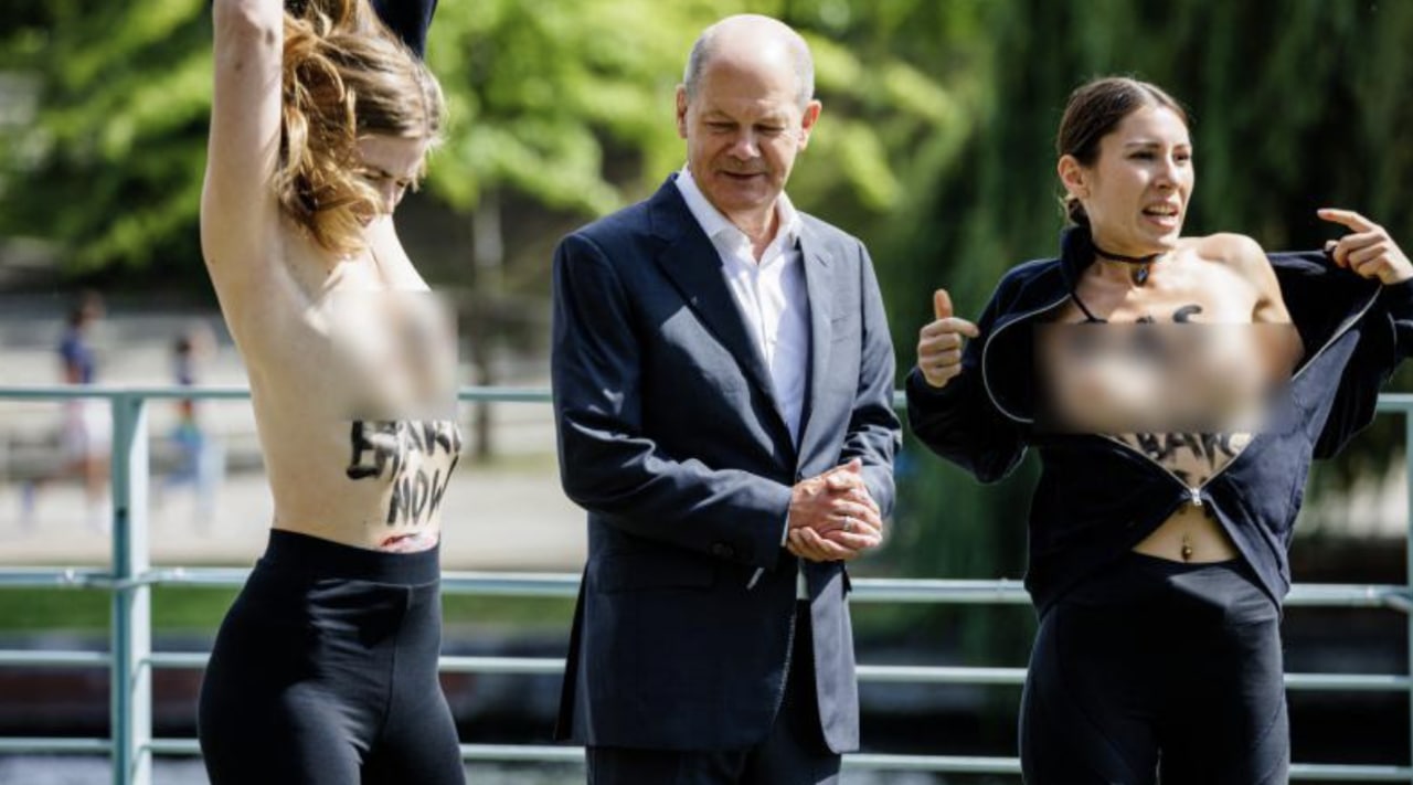 Două activiste l-au luat prin surprindere pe Olaf Scholz, scoțându-și tricourile fără niciun avertisment și pozând în sânii goi alături de cancelarul german, într-un gest de protest prin care cer „un embargo asupra gazului, acum” împotriva Rusiei